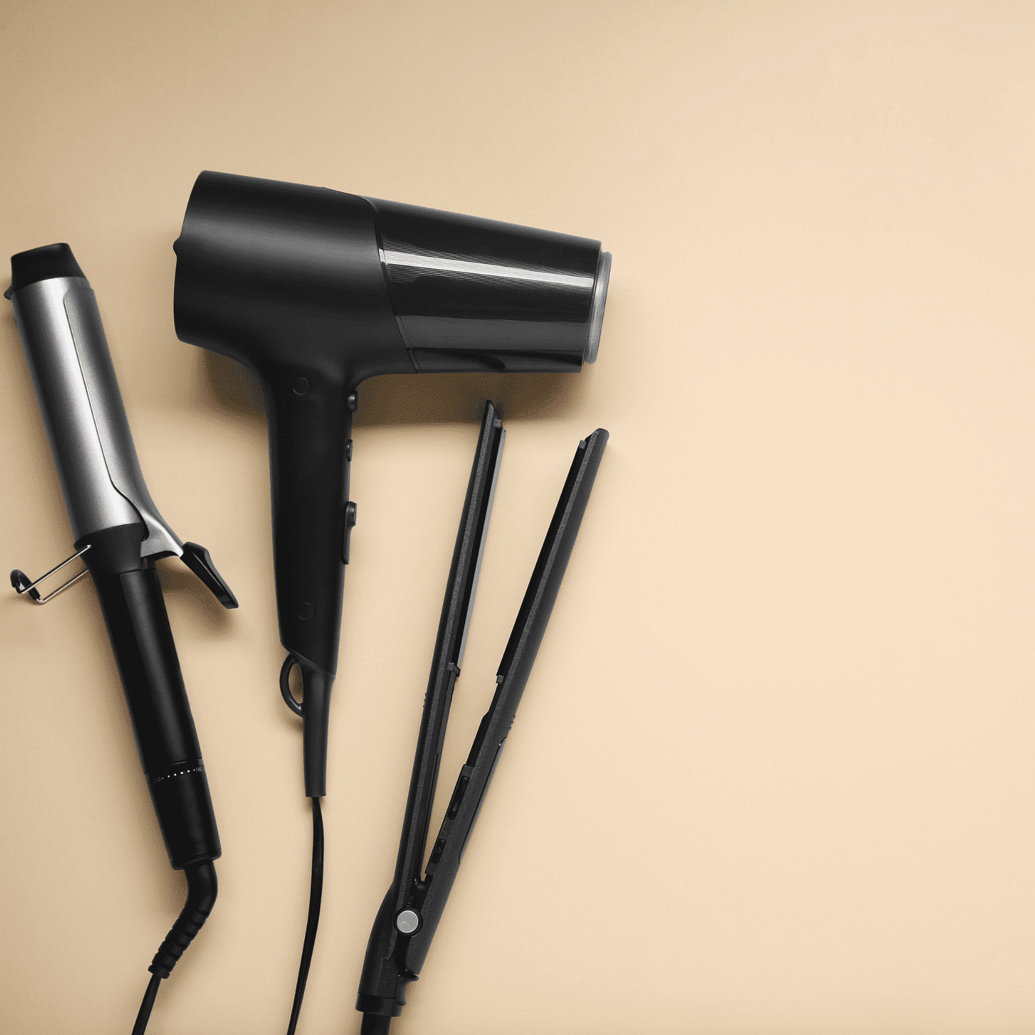 Hairdryer, curling iron, and straightener on beige background.